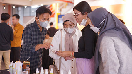 Salah satu tim program Wirausaha Merdeka Universitas Ciputra menjelaskan produk kepada pengunjung untuk mendapat masukan produk
